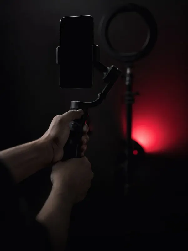 A phone on a gimbal being filmed under a red ring light
